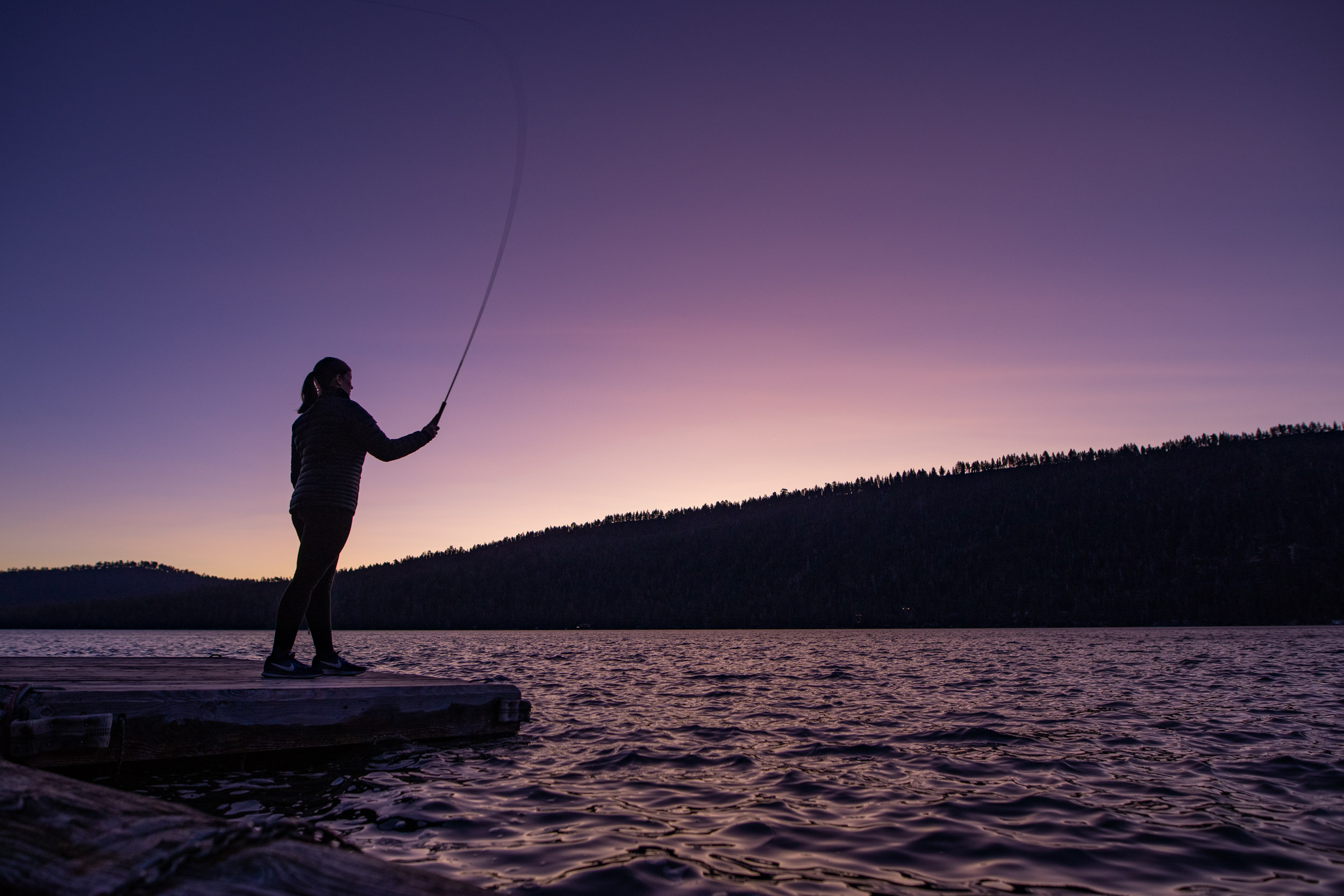 Woman fly fishes at dawn