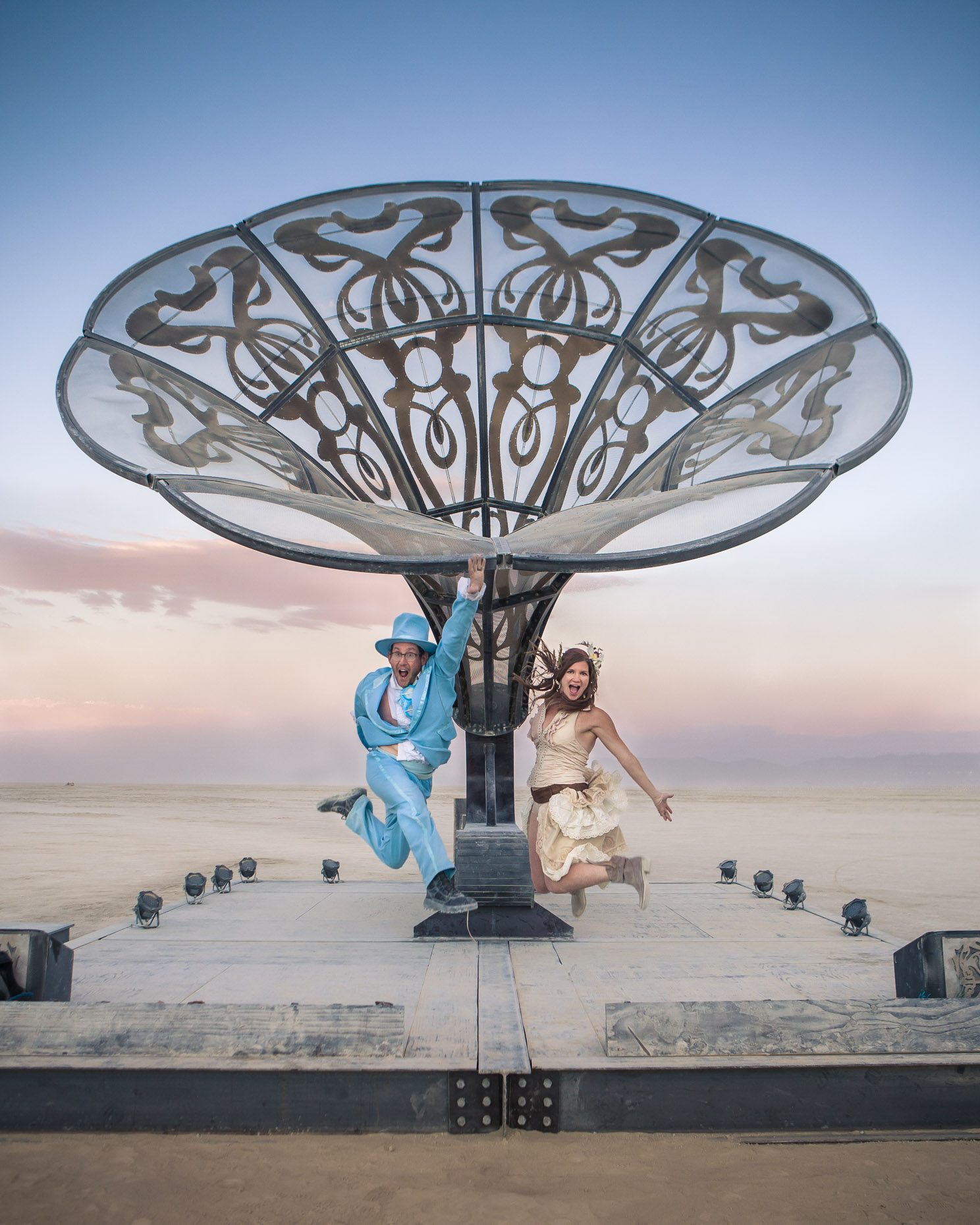 Couple jump in front of art sculpture at Burning Man