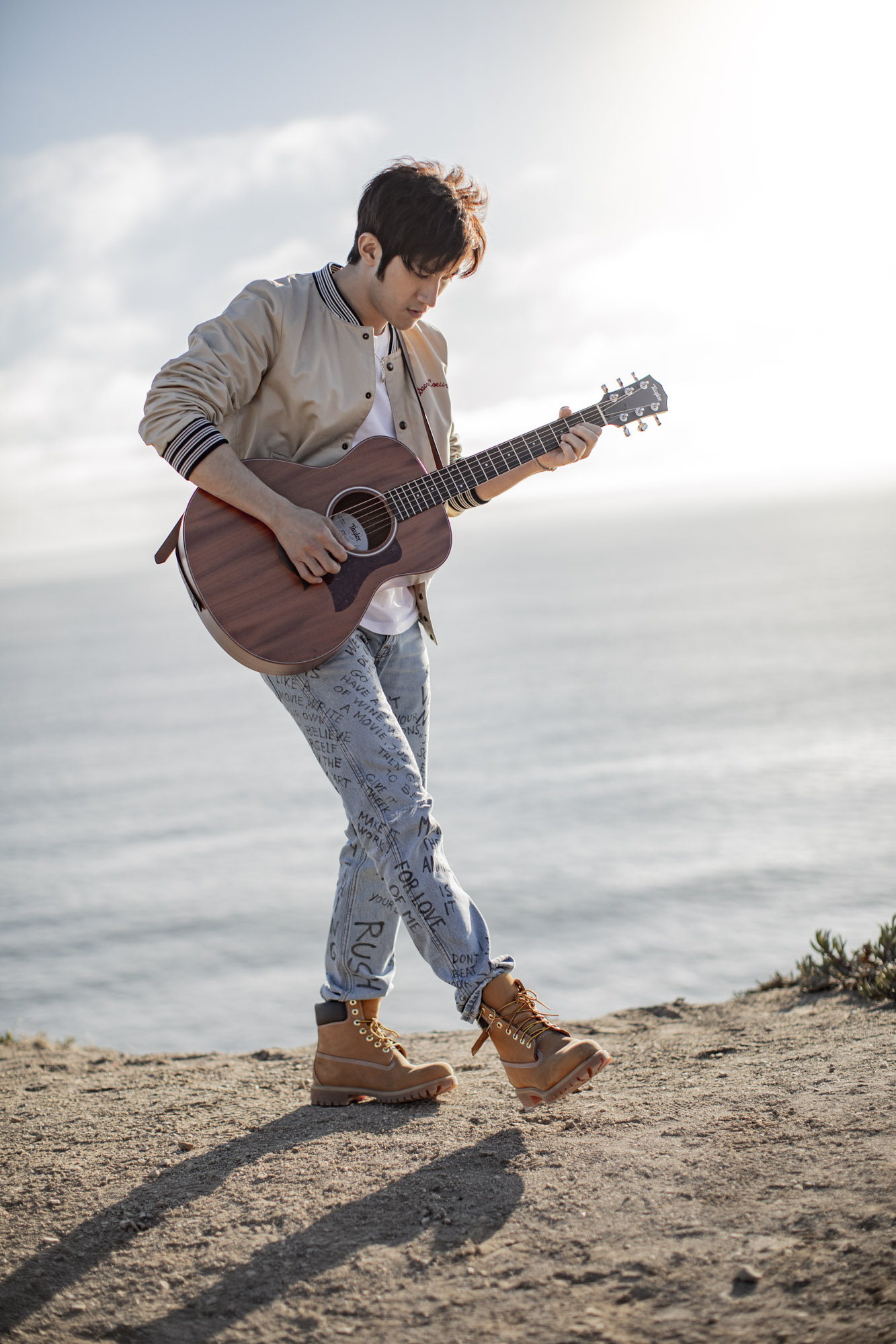 Man plays a guitar with the Pacific Ocean in the background