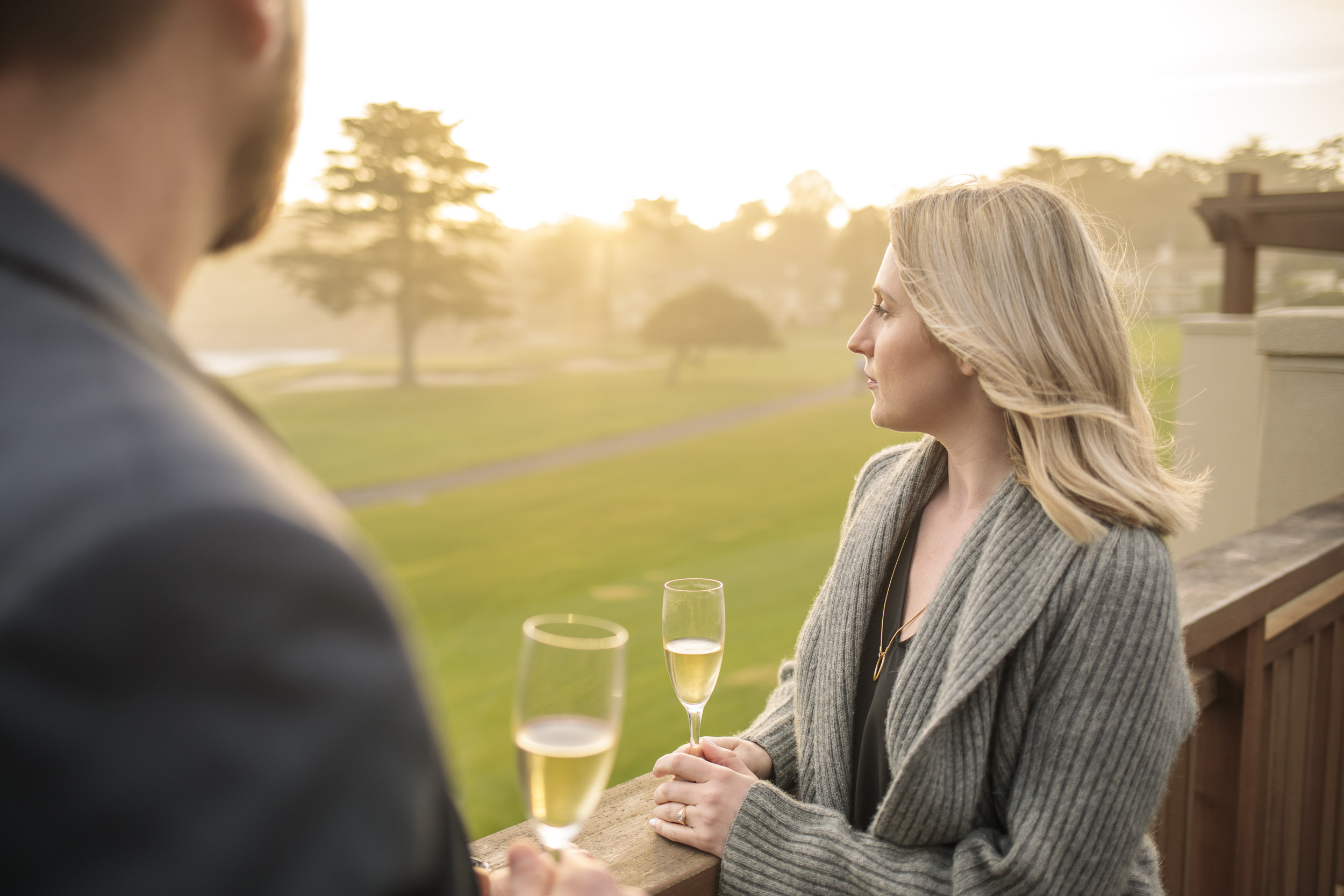 A couple enjoy a glass of champagne during sunset while over looking the 18th green at Pebble Beach.