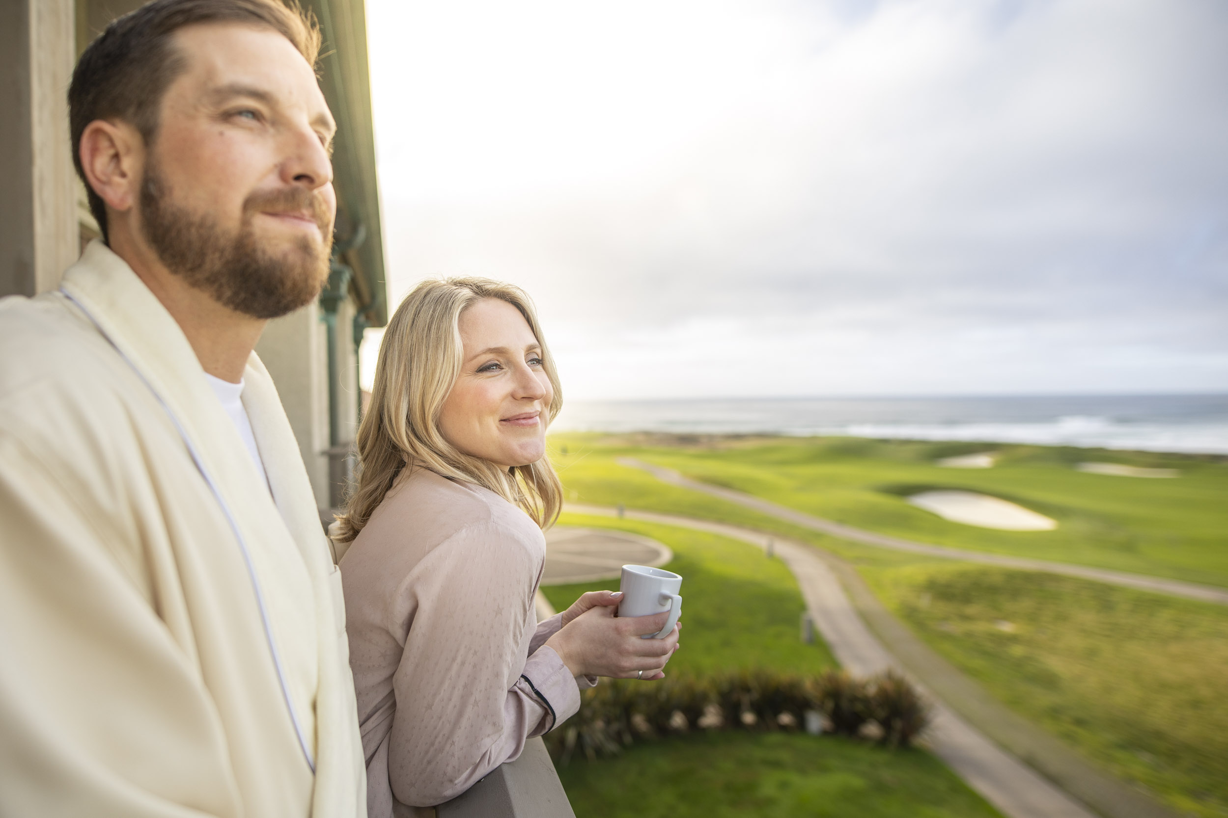 Man and woman enjoy their morning coffee and the ocean view over the Links at Spanish Bay.