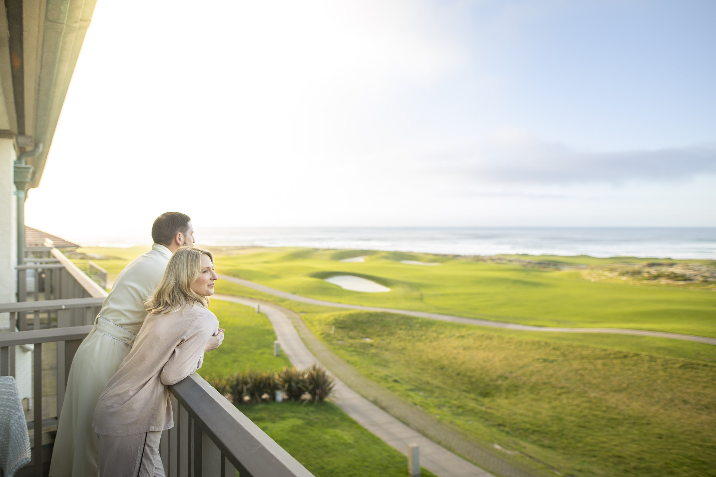 Man and woman enjoy their morning coffee and the ocean view over the Links at Spanish Bay.